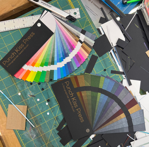 Color swatches and design tools on a cutting mat with 'Punch Kiss Press' branding.